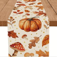 a table runner with autumn leaves and pumpkins on it