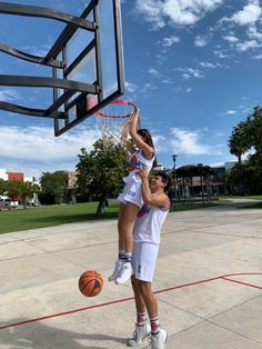 two people are playing basketball on an outdoor court