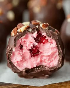 there is a piece of chocolate covered in pink ice cream and nuts on the side