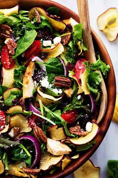 a salad in a bowl with apples, spinach and pecans on the side