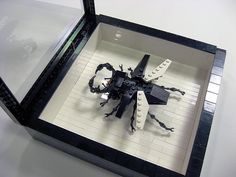 a lego model of a spider in a black and white display case on a table