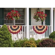 two potted flowers are hanging from the porch railing with an american flag banner on it