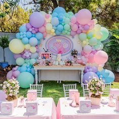 a table topped with lots of balloons next to a pink and blue dessert table covered in flowers