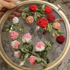 a person holding a embroidery project in their hand with flowers on the inside of it