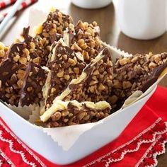 a bowl filled with chocolate and nuts on top of a red napkin next to a cup