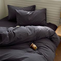 an unmade bed with two pillows and a bottle on the floor next to it