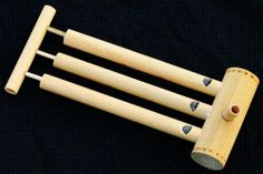 three wooden mallets with holes in them on a black background, one has two handles and the other has four bells