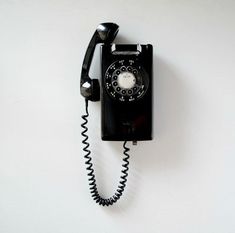 an old fashioned black telephone on a white wall