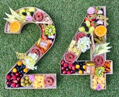 the number twenty four made out of fruits and vegetables is displayed on the grass with flowers