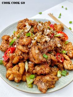 a white plate topped with fried chicken and veggies next to chopsticks