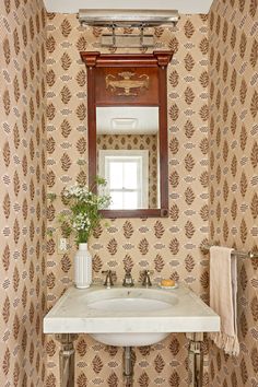 a white sink sitting under a mirror next to a wooden framed mirror above a bathroom sink