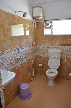 a bathroom with a toilet, sink and shower head mounted to the side of the wall