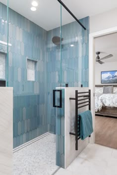 a bathroom with a glass shower door and blue tiles on the wall, along with a white tiled floor