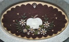 a white pumpkin sitting on top of a brown and beige rug with flowers around it