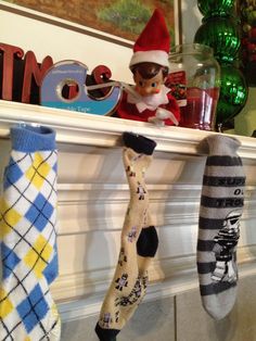 the elf is sitting on the mantle with three socks