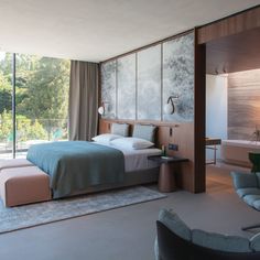 a bedroom with a large bed and two chairs next to a window that looks out onto the pool