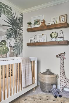 a baby's room with two shelves above the crib and a stuffed giraffe