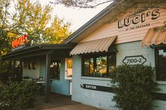 the outside of a restaurant with awnings over it's windows and bushes