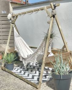 a hammock hanging from a wooden frame next to a potted plant on a patio