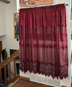 a red curtain hanging on the side of a wall in front of a painting and stairs