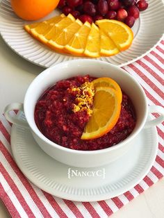 a bowl of cranberry sauce with orange slices and grapefruits on the side