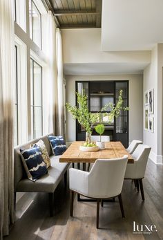 a dining room table with chairs around it and plants in the vases on top