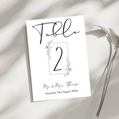 the wedding table numbers are displayed on top of a white card with black ink and flowers