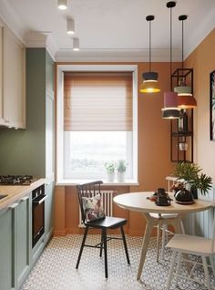 a small kitchen with an orange wall and white flooring, along with two chairs