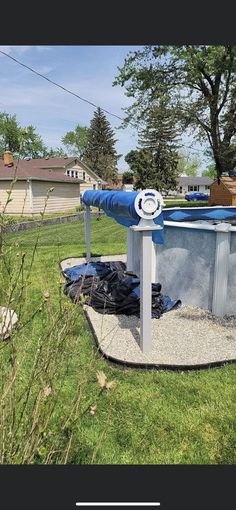 an above ground swimming pool in the middle of a yard with a blue cover over it