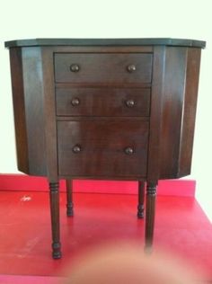 a wooden dresser sitting on top of a red floor next to a person's head