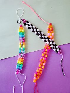 two pieces of colorful beaded string on a purple surface with pink and white background