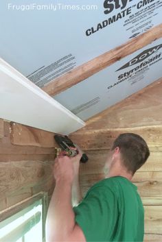 a man working on the side of a house with wood siding and plywood board