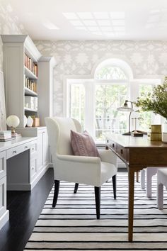 a white chair sitting in front of a wooden table on top of a black and white rug