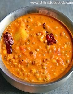 a metal bowl filled with soup on top of a table