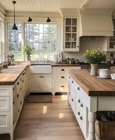 a large kitchen with white cabinets and wooden counter tops in front of an open window