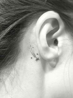 a woman's ear with a small dragonfly tattoo on her left behind the ear