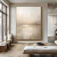 a large painting hanging on the wall in a living room with wood floors and white walls