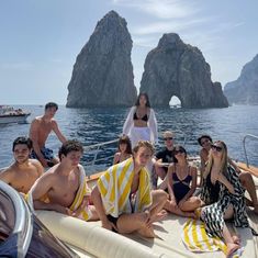 a group of people sitting on top of a boat in the ocean next to rocks