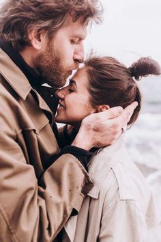 a man and woman standing next to each other near the ocean