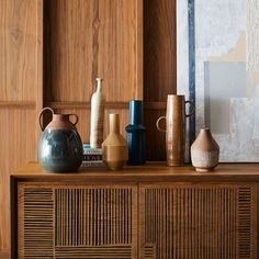 some vases are sitting on top of a wooden cabinet