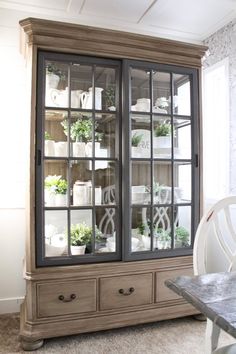 an old china cabinet with glass doors and plants