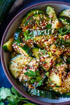 a bowl filled with zucchini and sesame seeds on top of a blue cloth