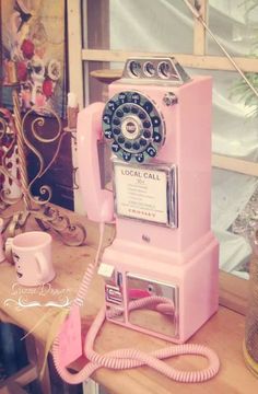 an old pink phone sitting on top of a wooden table