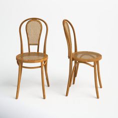 two wooden chairs sitting side by side in front of a white background, one with wicker back and the other without