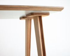 a close up of a wooden table with white walls in the background and wood legs