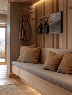 a living room filled with lots of pillows on top of a wooden bench next to a door