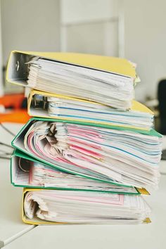 a stack of folders sitting on top of a white table next to a computer