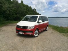 a red and white van parked on the side of a road next to a body of water