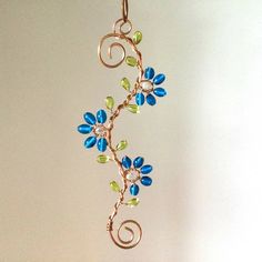 a necklace with blue and green flowers hanging from it's side on a chain