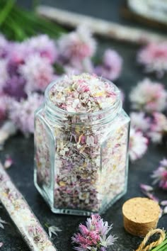 a jar filled with lots of flowers next to a wooden stick and some other items